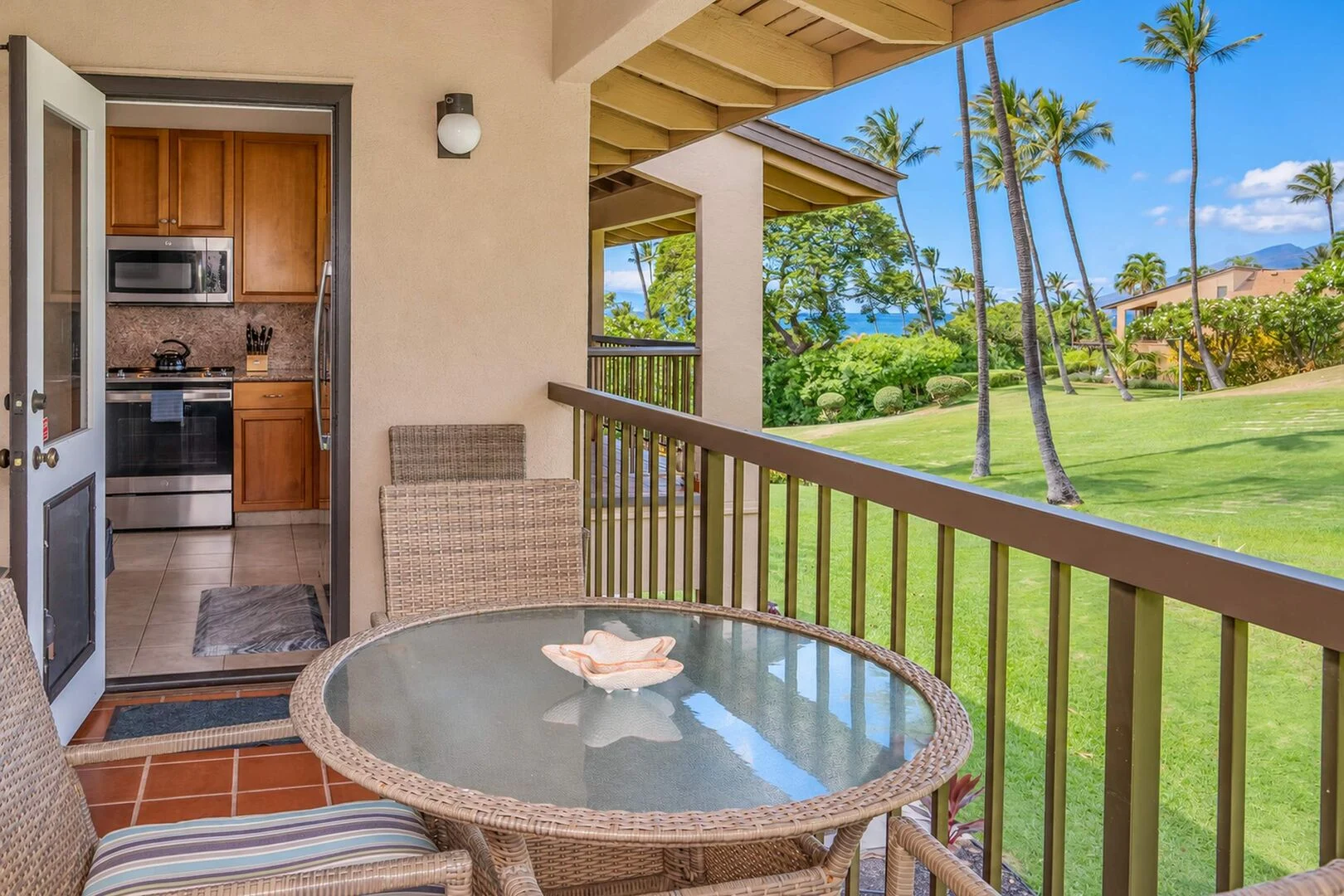 Private lanai with dining table, ocean glimpse, and kitchen door