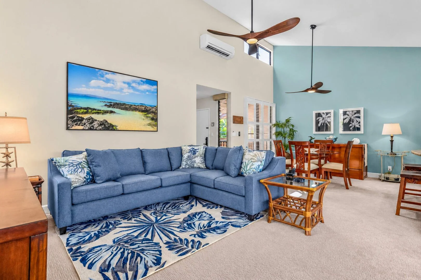 Living room with sectional sofa, tropical art, and split A/C