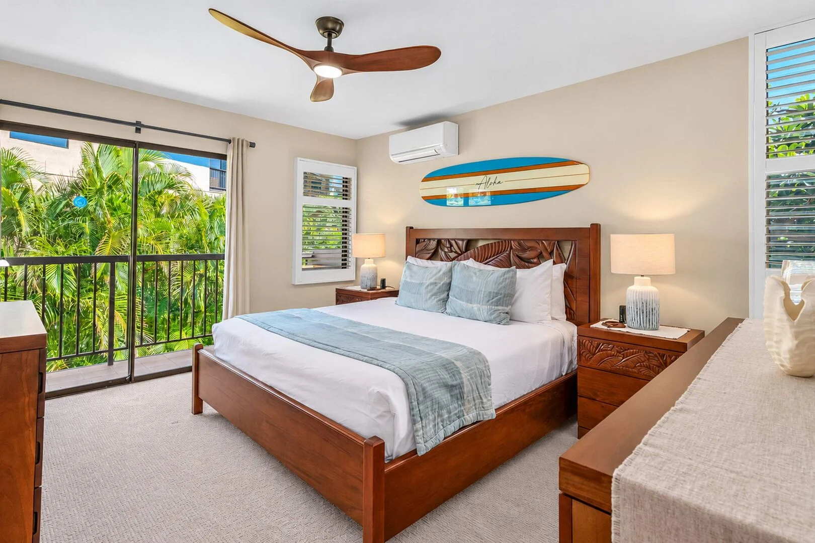 Bedroom with carved wood bed, surfboard decor, and garden balcony